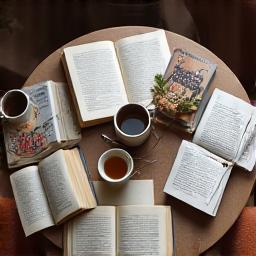 Variedad de libros abiertos y tazas de café en una mesa redonda, ambiente de club de lectura